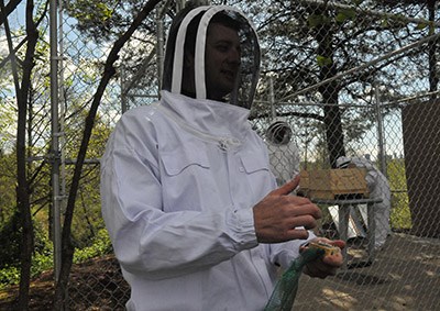 Jay Ashworth, marketing and sustainability manager at Associated Labels, shows staff the caged queen bee that will go into the Coquitlam company's new parking lot apiary.